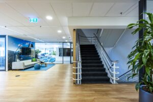 Moderne en lichte kantoorruimte aan de Johan Huizingalaan met een trap, zithoek en glazen vergaderruimtes.
